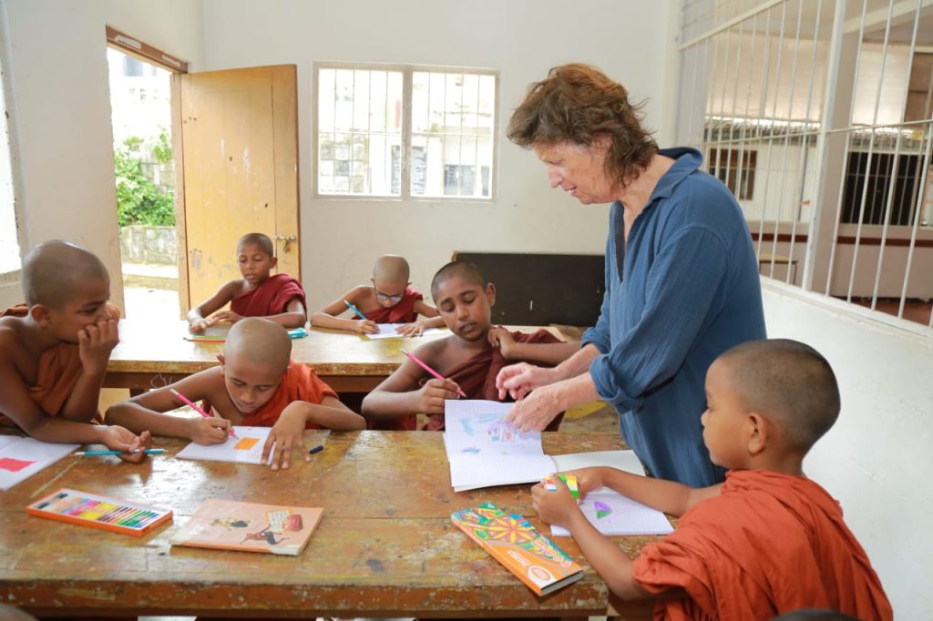 Volunteer helping young Buddhist monks with classroom work