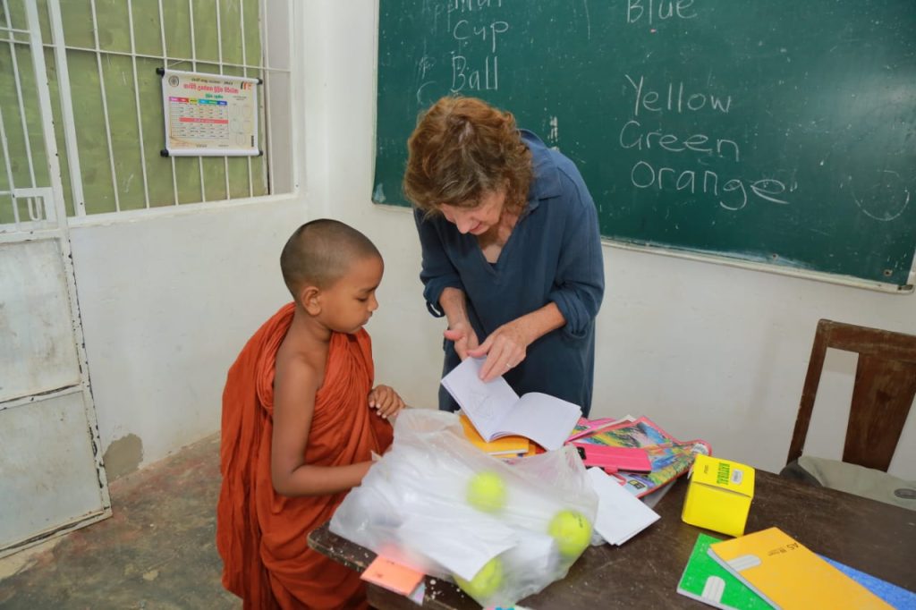 Volunteer helping a young Buddhist monk with his workbook